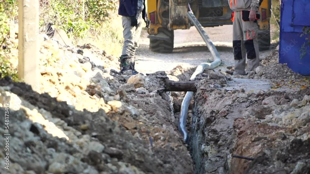 Plastic pipes laid in trenches. Workers are installing water pipeline under a city street in a trench. New pipeline in a process of building, under construction. Workers are laying pipeline. Close up Plastic pipes laid in trenches. Workers are installing water pipeline under a city street in a trench. New pipeline in a process of building, under construction. Workers are laying pipeline. Close up