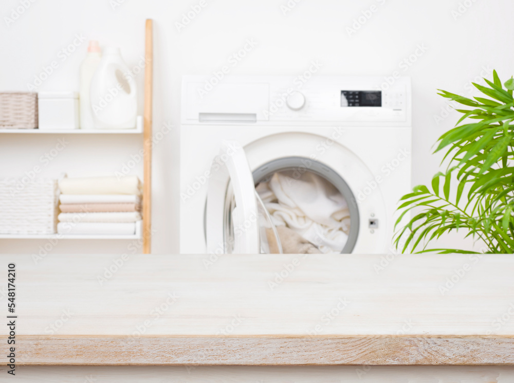 Empty wooden table in blurred laundry room with washing machine - obrazy, fototapety, plakaty 