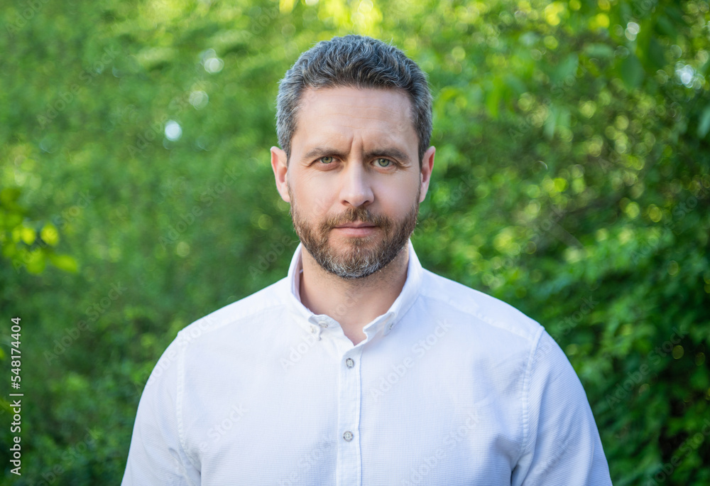 Portrait of handsome manager with unshaven face in white shirt natural background Portrait of handsome manager with unshaven face in white shirt natural background