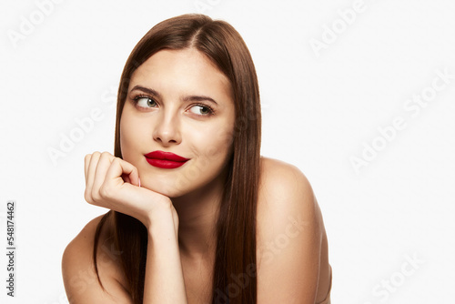 Portrait of young beautiful brunette girl with straight hair and red lips posing isolated over white background. Concept of beauty, fashion and cosmetology
