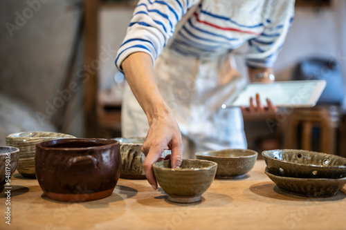 デジタルタブレットを使って商品管理をする陶芸家の女性