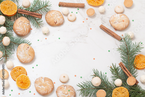 candies and cookies with christmas tree branches on white marble background