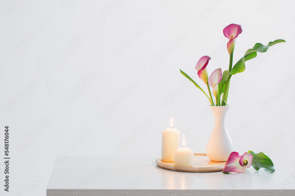 pink calla lily in vase and burning candles on white background pink calla lily in vase and burning candles on white background