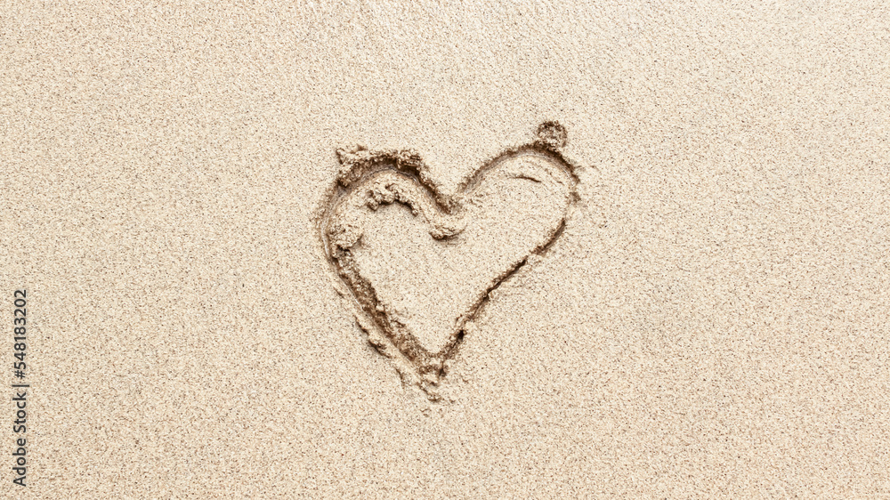 The word LOVE is writting on the sand with wave. drawing on the sand. writing with sands on the beach.