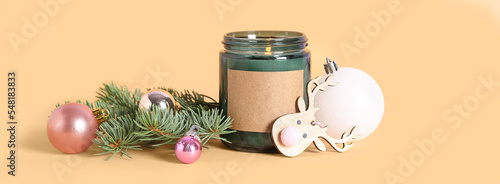 Foto Jar with burning candle, Christmas decor and fir branches on beige background