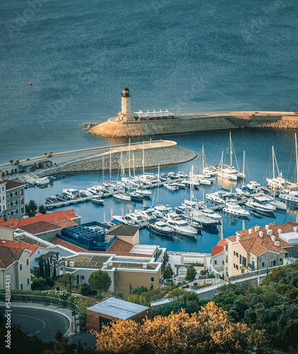 Foto Vertical shot from a hill to buildings and boats on a harbor by a coastline