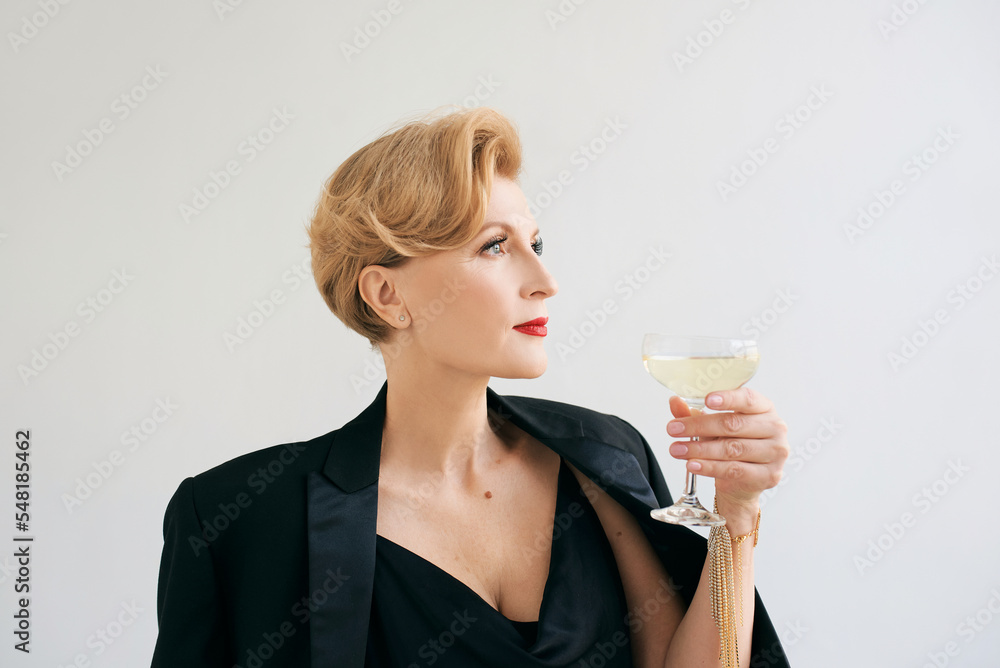 mature stylish elegant woman in tuxedo with glass of sparkling wine. Party, celebration, anti age concept mature stylish elegant woman in tuxedo with glass of sparkling wine. Party, celebration, anti age concept
