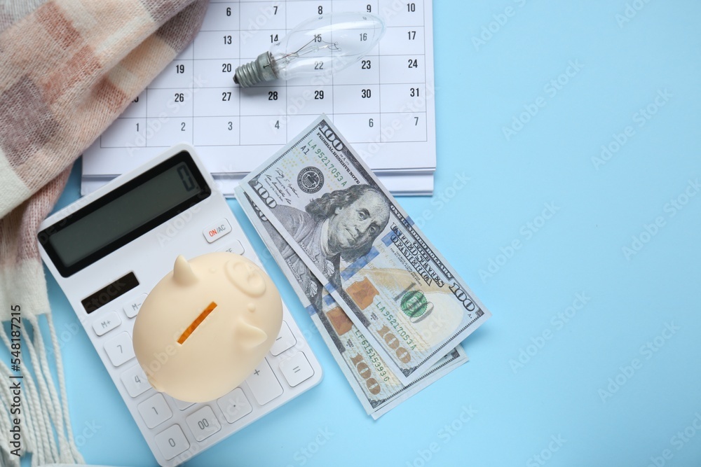 Fototapeta premium Flat lay composition with piggy bank and calculator on light blue background. Space for text