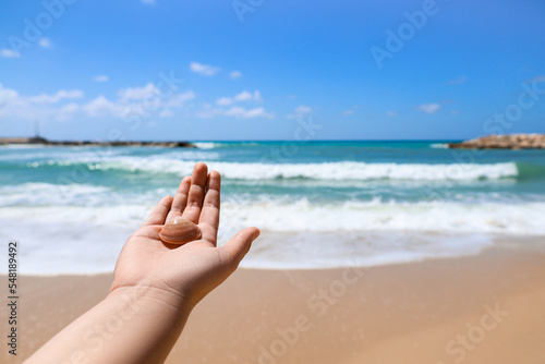 Woman with seashell on beach, closeup