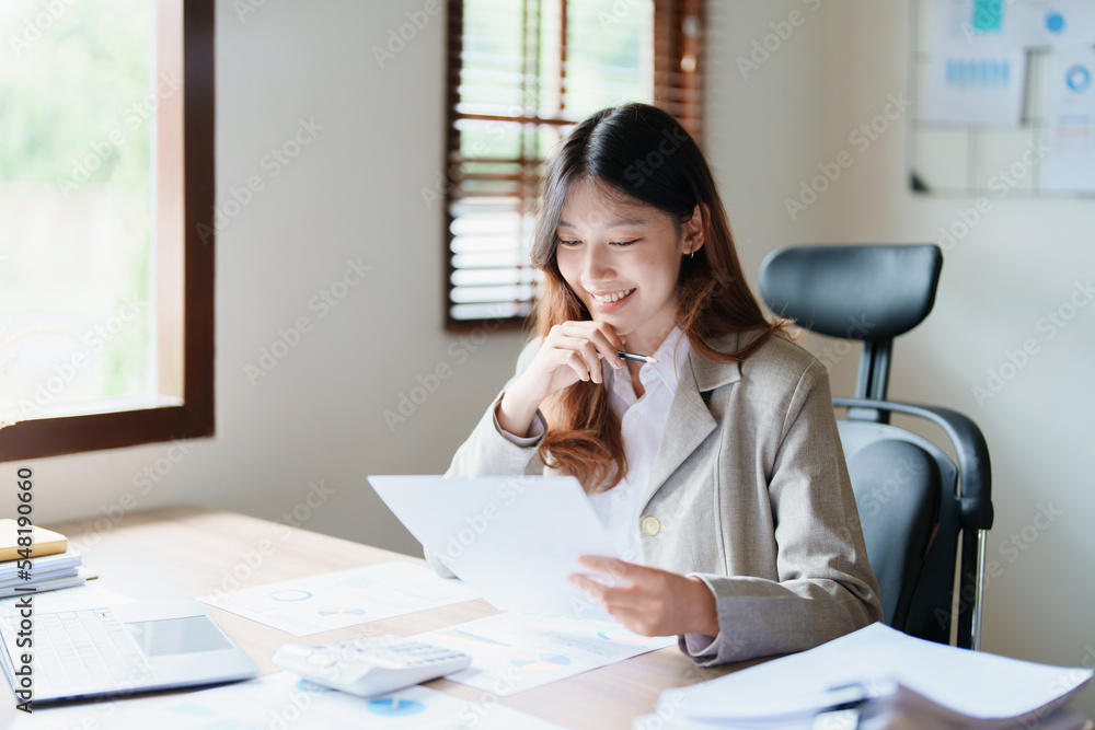 financial, Planning, Marketing and Accounting, portrait of Asian employee checking financial statements using documents and computer laptop at work financial, Planning, Marketing and Accounting, portrait of Asian employee checking financial statements using documents and computer laptop at work
