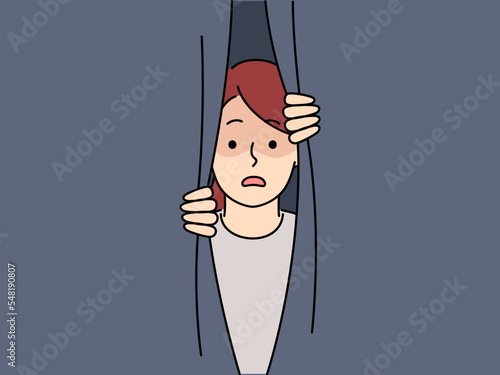 Scared girl peeping behind curtain 