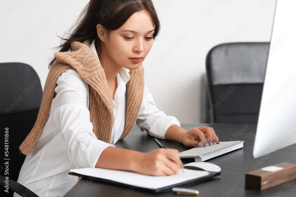 Young Asian woman working with computer at table in office Young Asian woman working with computer at table in office