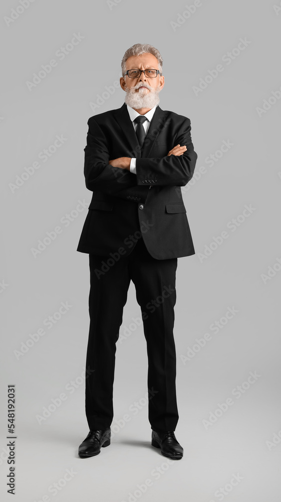 Senior bearded man in eyeglasses and black suit on grey background Senior bearded man in eyeglasses and black suit on grey background