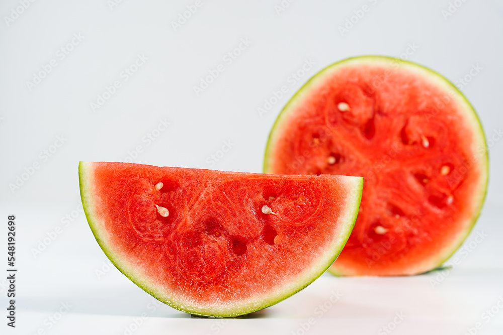 Red watermelon slice close-up on white background, space for text. Half of a ripe scarlet watermelon fruit with red juicy flesh and seeds turned sideways in profile, text space above. Red watermelon slice close-up on white background, space for text. Half of a ripe scarlet watermelon fruit with red juicy flesh and seeds turned sideways in profile, text space above.