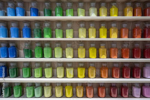 Colorful paint bottles on wooden shelves