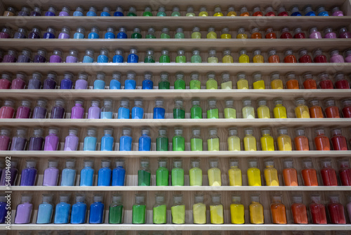 Colorful paint bottles on wooden shelves