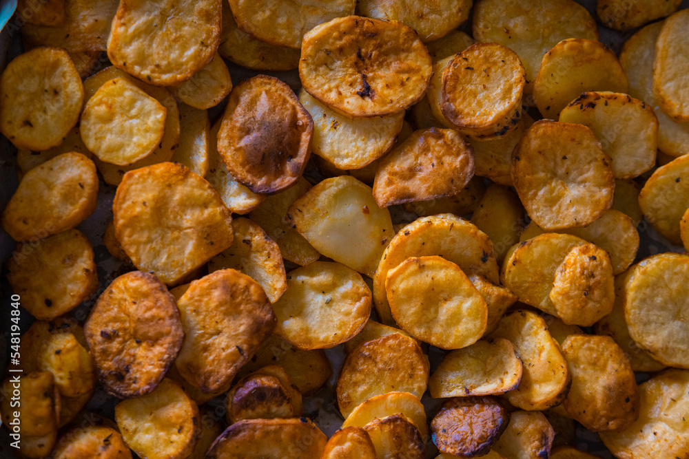 Sliced potato chips or dollar chips looking from above lying in a pan. Freshly baked from oven potato chunks. Sliced potato chips or dollar chips looking from above lying in a pan. Freshly baked from oven potato chunks.