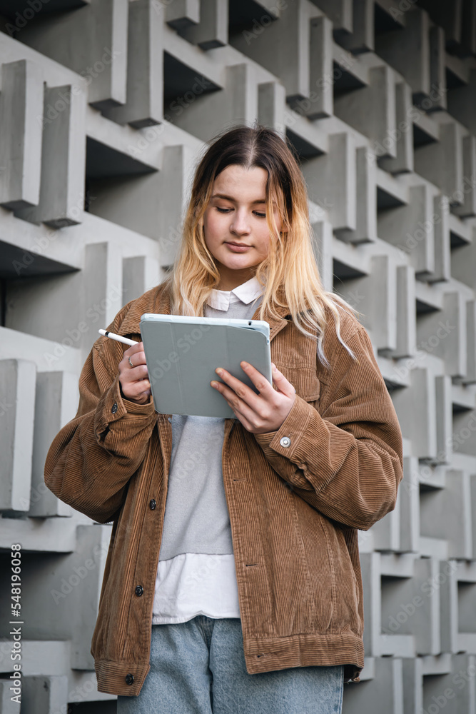 Attractive young woman draws with a pencil on a digital tablet. Attractive young woman draws with a pencil on a digital tablet.