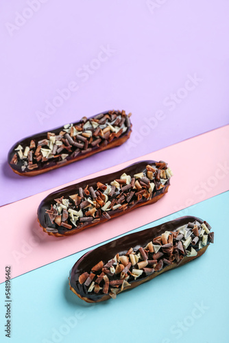 Sweet chocolate eclairs on color background