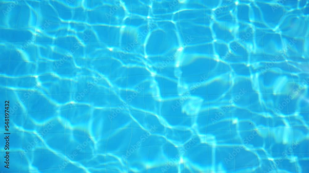 Crystal clear water with rippling sunlight in swimming pool. Bright sun beams reflecting and sparkling on surface of aqua. Beautiful background. Slow motion Close up Top view Crystal clear water with rippling sunlight in swimming pool. Bright sun beams reflecting and sparkling on surface of aqua. Beautiful background. Slow motion Close up Top view