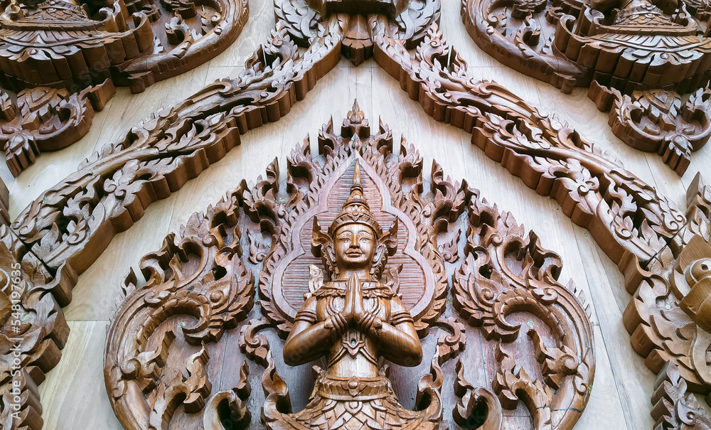 Low angle view of wood carving deva clasping hand pattern on teak wooden wall of Wat Krok Krak temple at Samut Sakhon, Thailand - obrazy, fototapety, plakaty 