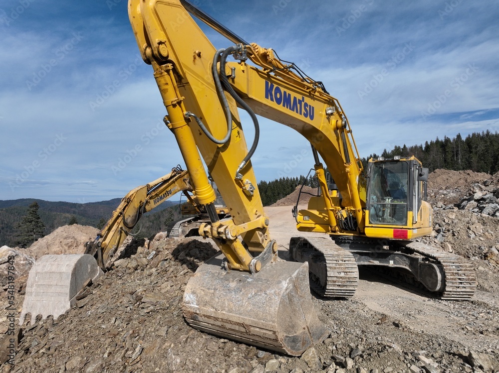 Obraz premium Industrial mine excavators are digging the soil in the construction site and loading trucks. Aerial drone top view. 