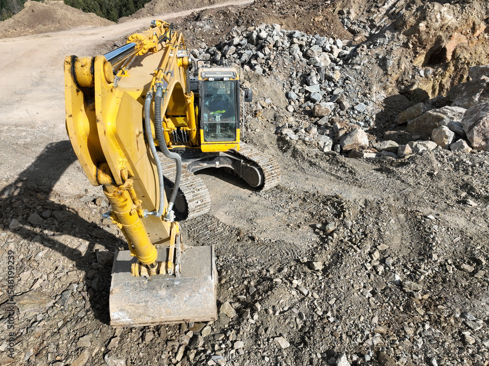 Industrial mine excavators are digging the soil in the construction site and loading trucks. Aerial drone top view. 