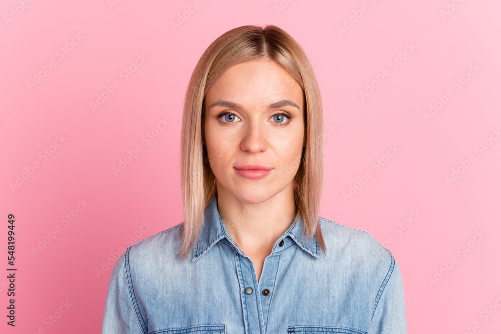Headshot of serious young female wearing shirt looking at camera standing isolated at pastel studio wall