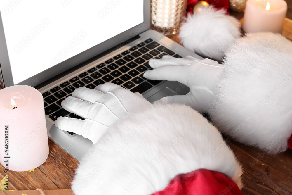 Santa Claus using laptop on wooden table, closeup Santa Claus using laptop on wooden table, closeup