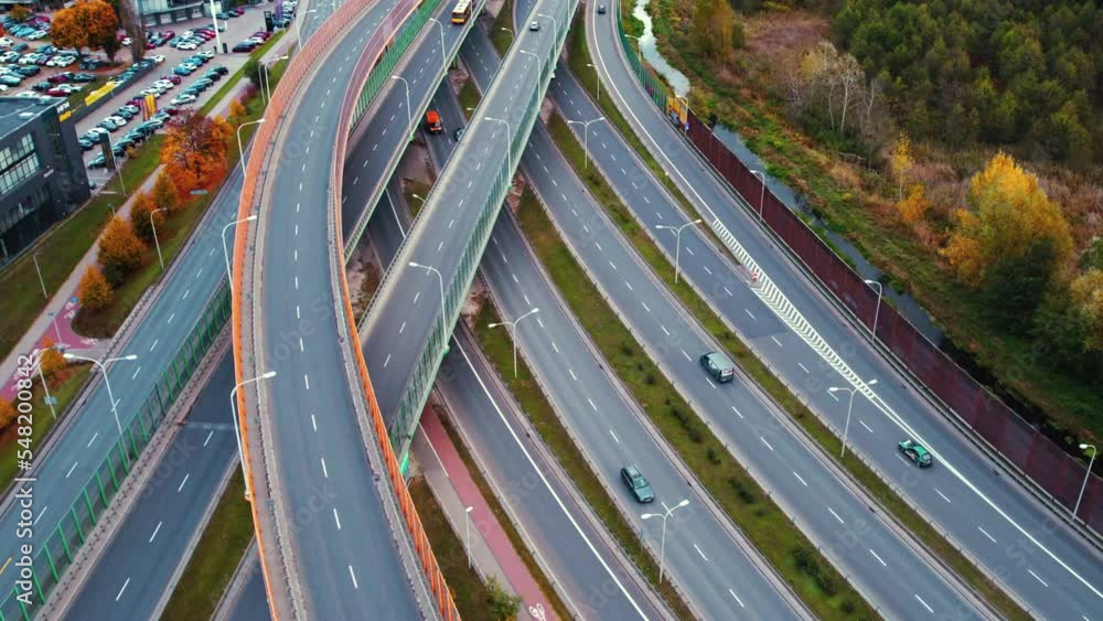 Aerial view of road intersection with fast moving cars and trucks, no traffic. Modern construction design of elevated roads to avoid traffic jams. High quality 4k footage
