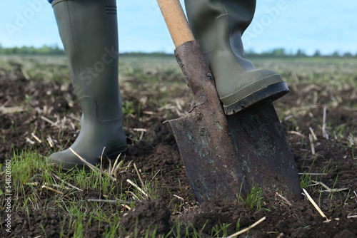 Man digging soil with shovel in field, closeup