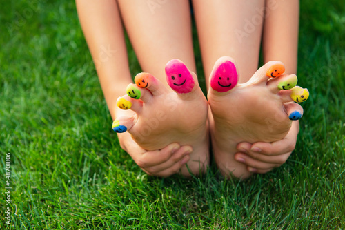 Teenage girl with smiling faces drawn on toes outdoors, closeup © New Africa