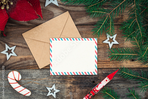 Blank paper, envelope and Christmas decor on wooden background, copy space.
