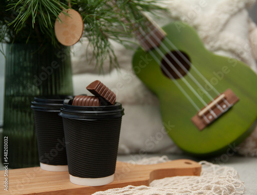 Morning cocoa in black cups, Christmas tree and ukulele nearby. Merry Christmas
