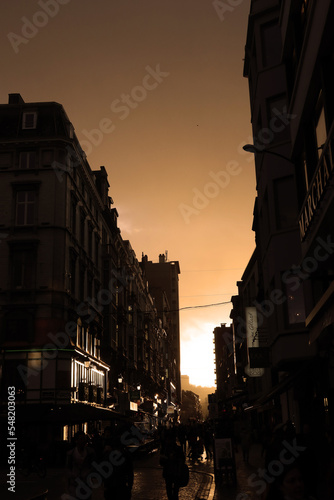 a busy belgium shopping street in liege, at evening in the sunset.