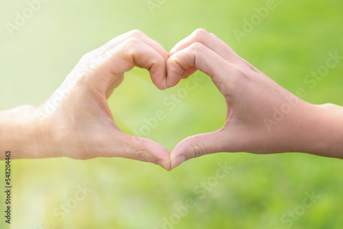 Couple making heart with hands outdoors, closeup © New Africa
