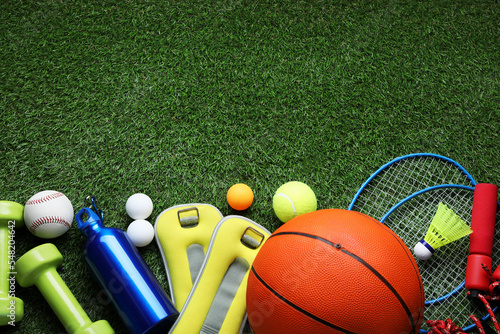 Set of different colorful sports equipment on green grass, flat lay. Space for text