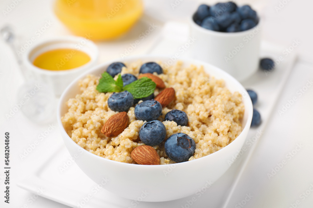 Bowl of delicious cooked quinoa with almonds and blueberries on white table, closeup Bowl of delicious cooked quinoa with almonds and blueberries on white table, closeup