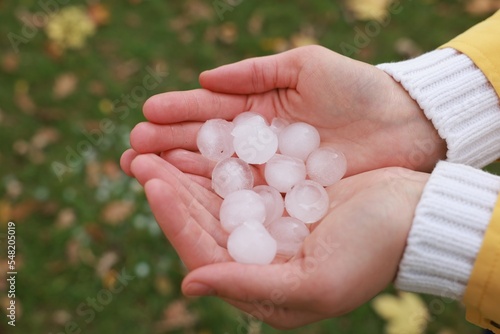 Woman holding hail grains after thunderstorm outdoors, closeup