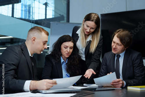 Female business leader writing on paper at meeting in office