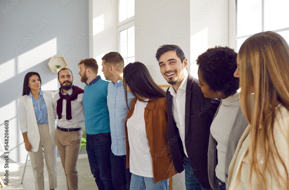 Diverse business team embracing teamwork and having fun together. Multicultural group of happy cheerful supportive people standing in office, hugging each other and smiling. Support, teamwork concept Diverse business team embracing teamwork and having fun together. Multicultural group of happy cheerful supportive people standing in office, hugging each other and smiling. Support, teamwork concept