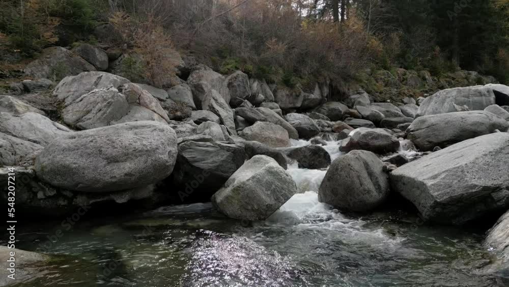 Cold water flows down the stream. Autumn in the forest and cool mood. Big stones in the riverbed. Aerial shot Cold water flows down the stream. Autumn in the forest and cool mood. Big stones in the riverbed. Aerial shot