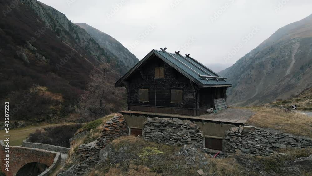 Wooden House And Old Arch Bridge With Alpine Mountains At Background Near Nufenen Pass, Ulrichen, Valais, Switzerland. Aerial Drone Shot Wooden House And Old Arch Bridge With Alpine Mountains At Background Near Nufenen Pass, Ulrichen, Valais, Switzerland. Aerial Drone Shot