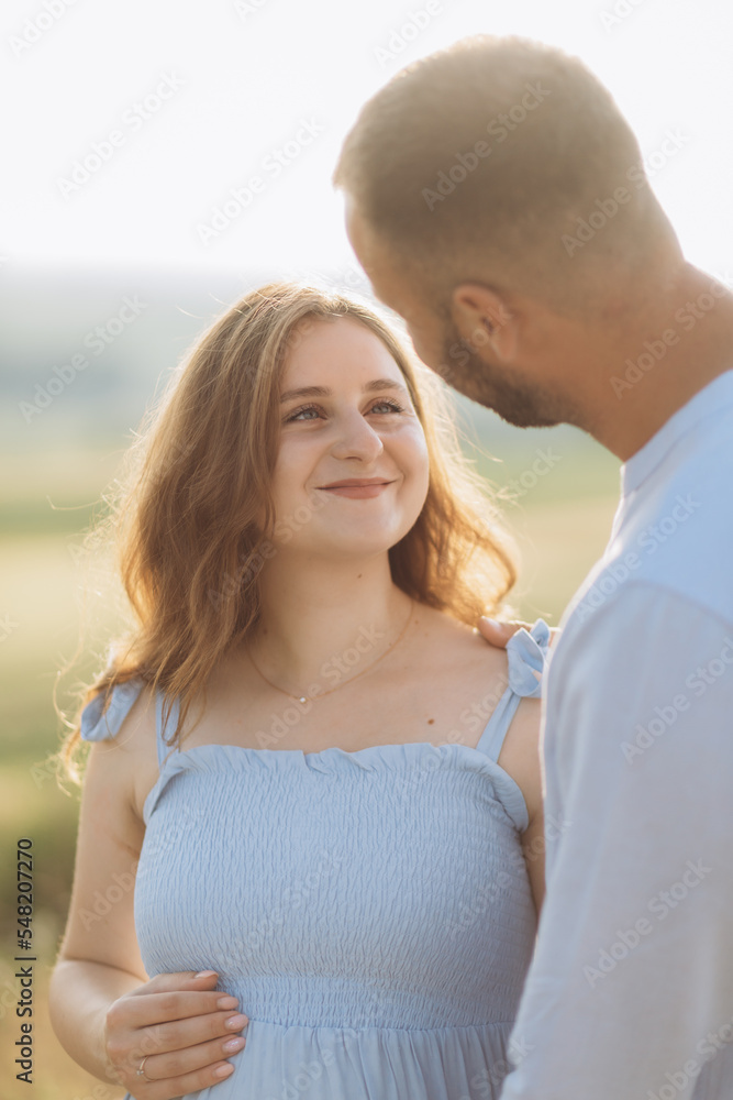 Portrait of a lovely couple standing together on the greenfield. Happy couple expecting a baby, young family concept