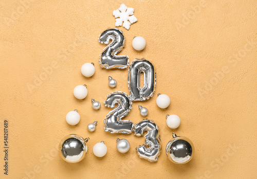 Christmas tree made of figure 2023 and balls on beige background