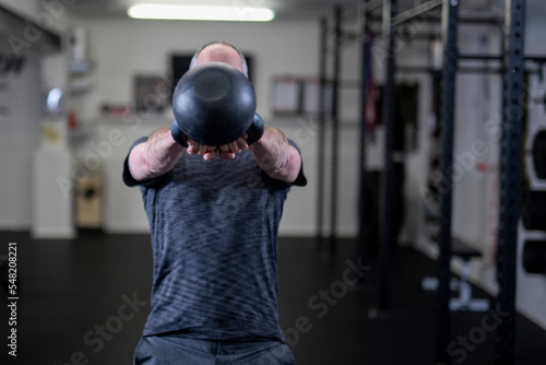 Low section of man lifting kettlebell in gym