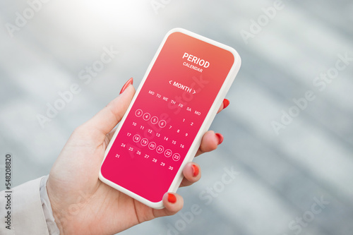 Menstruation calendar. Woman tracking periods by using menstrual calendar app on phone photo