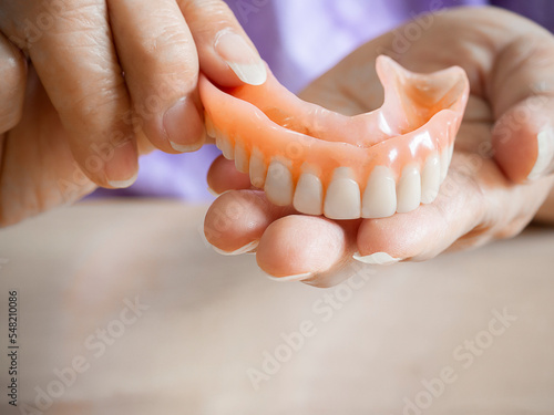 Close up of hands of elderly woman holding a denture.