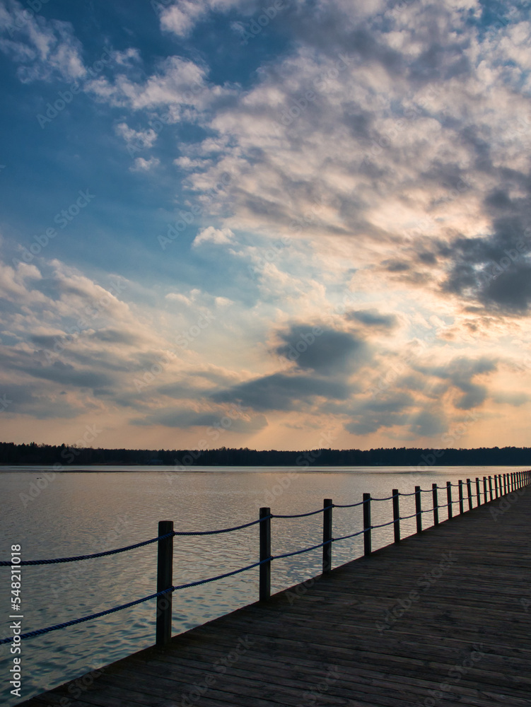 Late afternoon over a pier. Blue and orange sky over a lake. Late afternoon over a lake side.