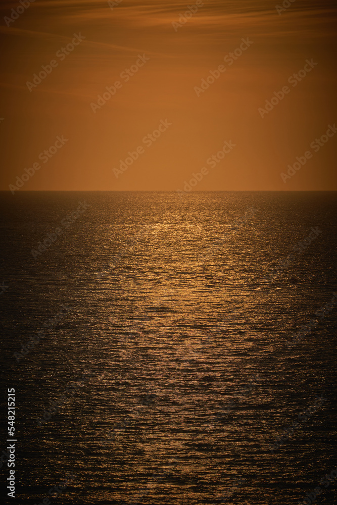 A vertical photograph of a moody dark orange sea view